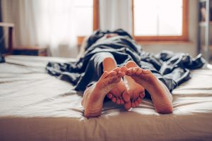 Adult couple's feet looking out of bed