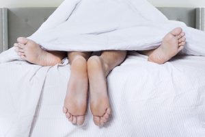 Low Section Of Couple In Bed At Home