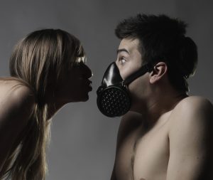 Naked Caucasian woman breathing on man wearing pollution mask
