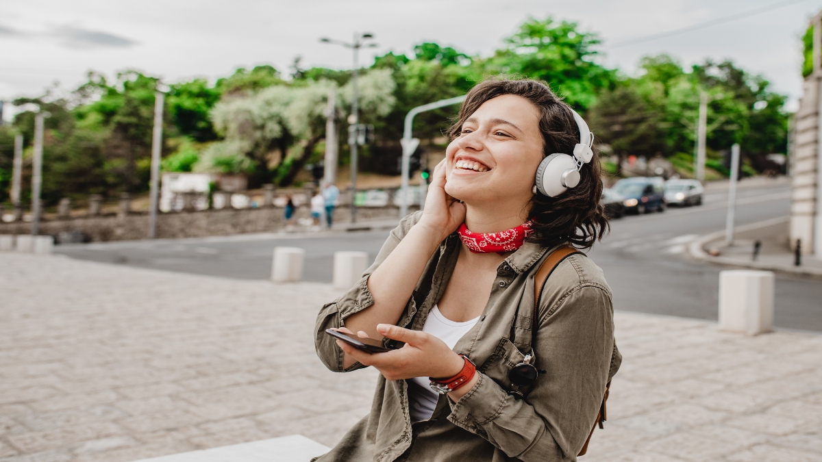 Mujer escuchando música a través de su celular (Foto vía Getty Images)